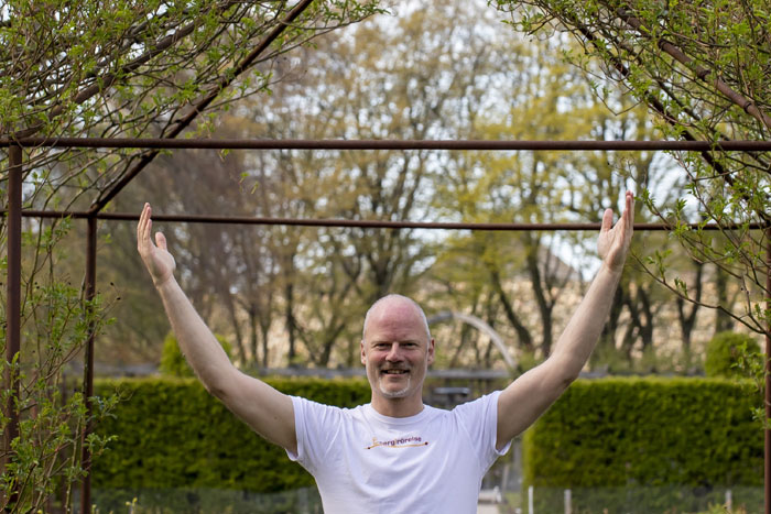Person standing in a garden with hands in the air doing qigong